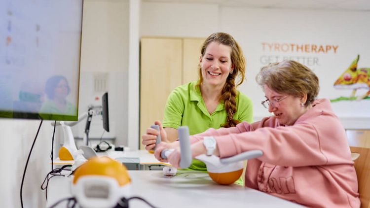 Eine Therapeutin unterstützt die Patientin bei der Armtherapie